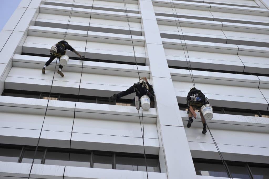 3 men abseil window cleaning on a building